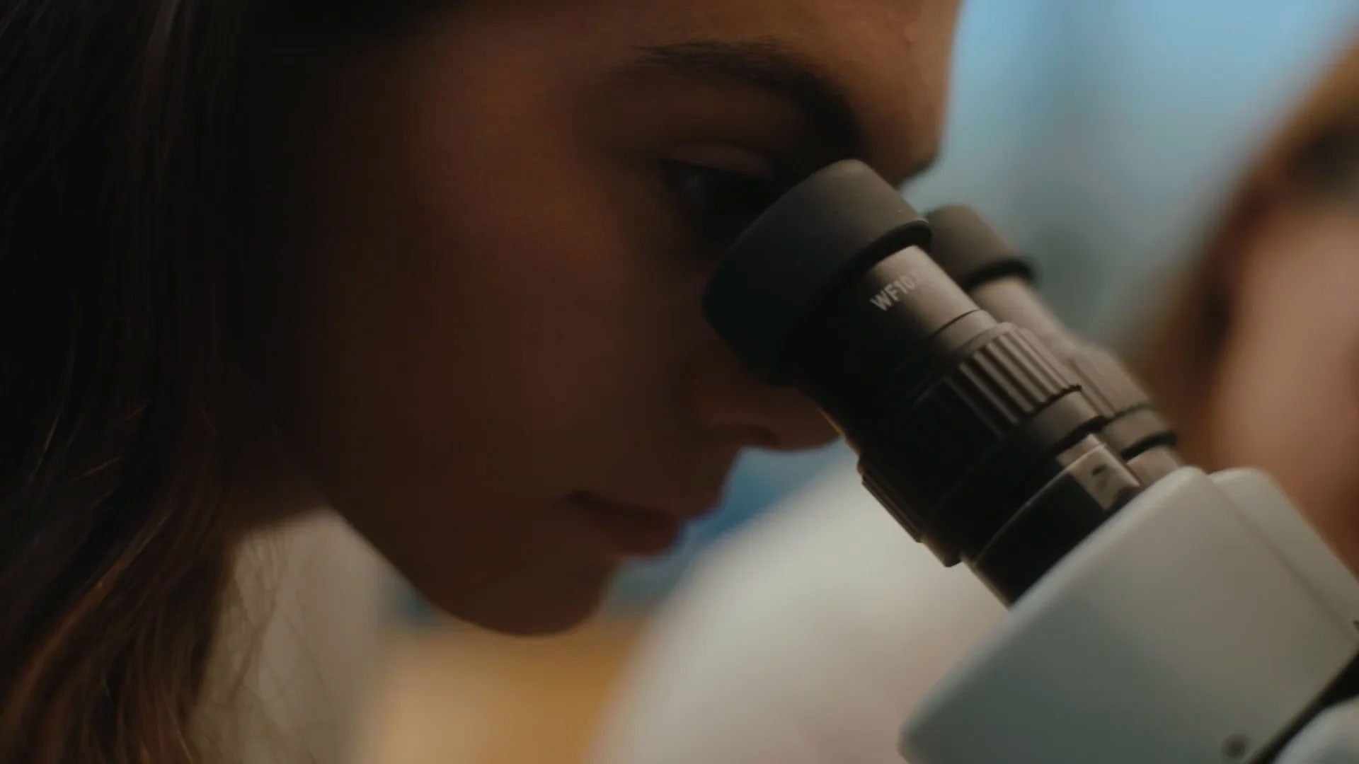 Image of a student using a microscope in a laboratory setting, highlighting hands-on learning and scientific exploration.