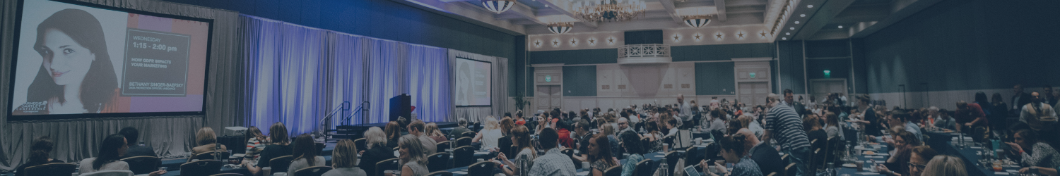 Image showing a large crowd attending a conference, with attendees seated and focused on a speaker, creating a professional and engaging atmosphere.