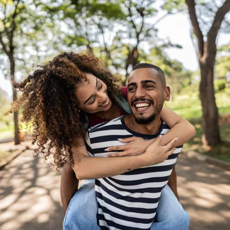 Woman wrapping arms around man outdoors.