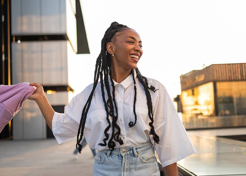Woman walking through a campus swinging her jacket to the side
