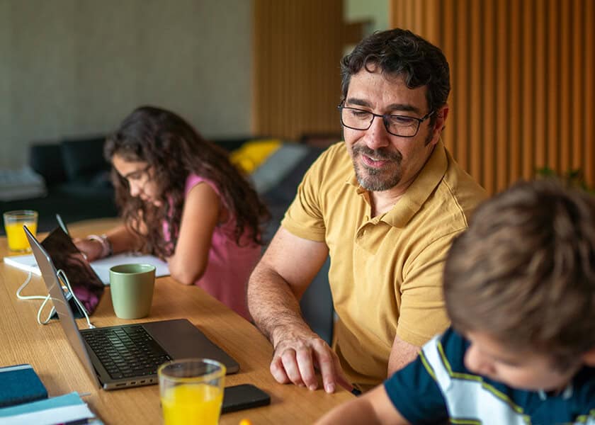 Man sitting with kids in front of laptops
