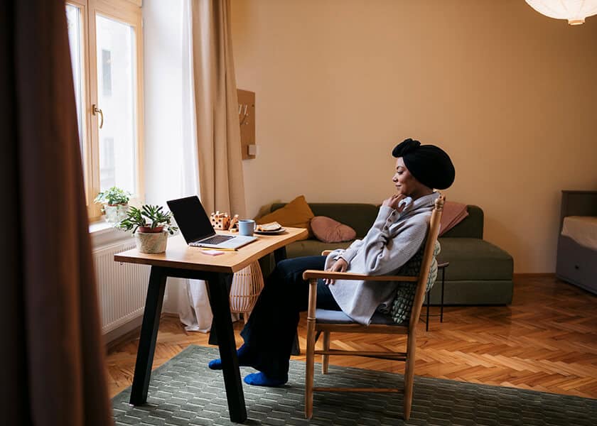 Woman in living room seated at desk with laptop