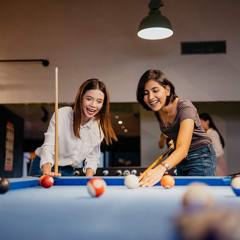 Two women playing pool and laughing
