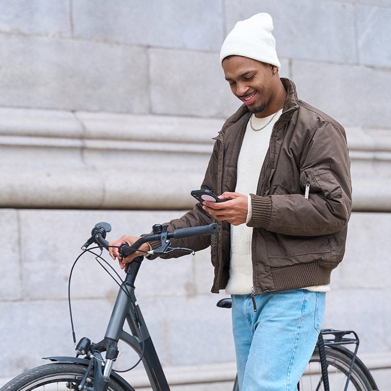 Man walking bike looking at cellphone