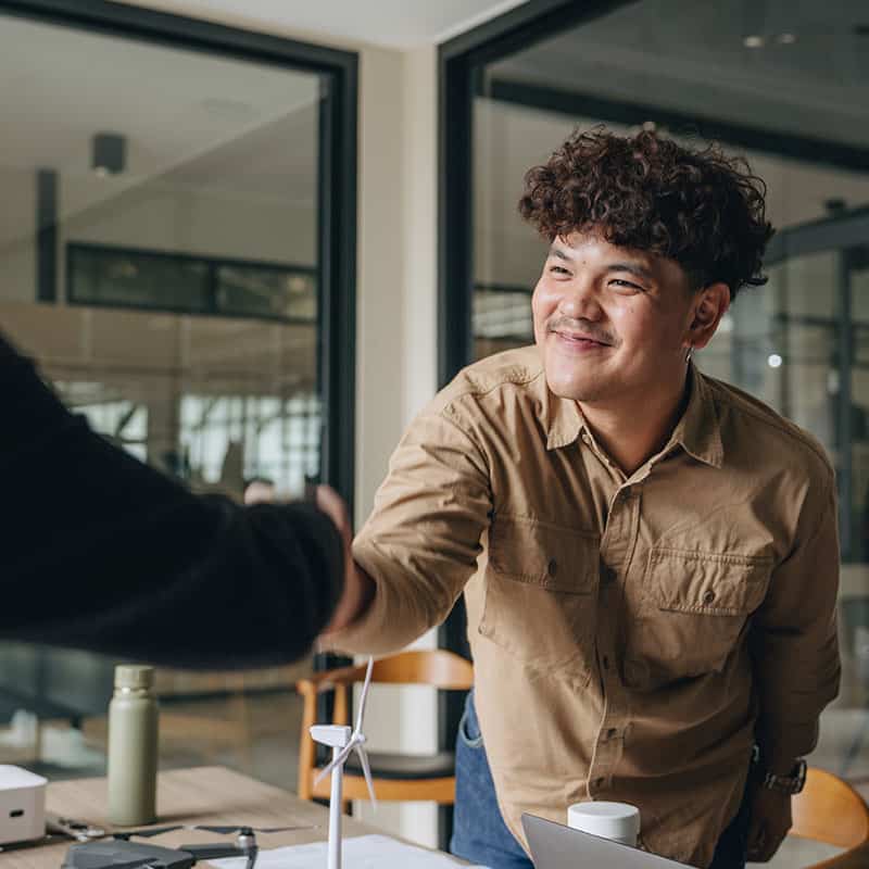 Man shaking someones hand across a desk