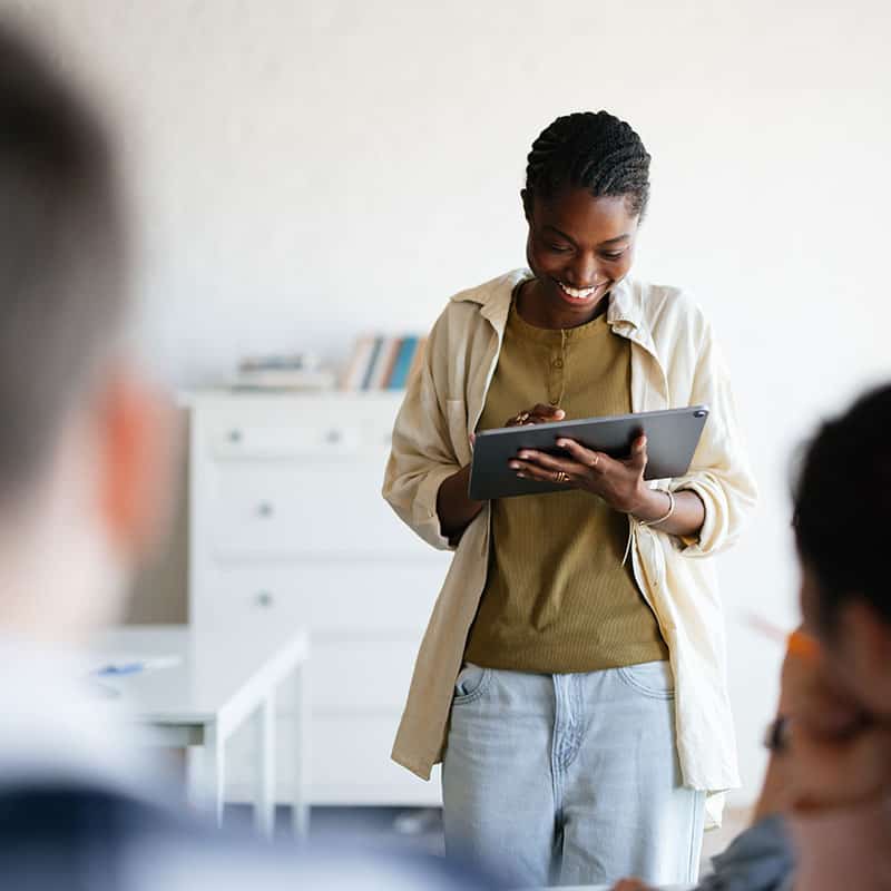 Woman on computer tablet in front of class