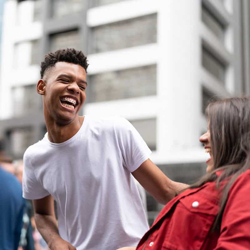 Man and woman laughing with buildings in background