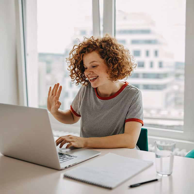 Woman waving in front of a laptop