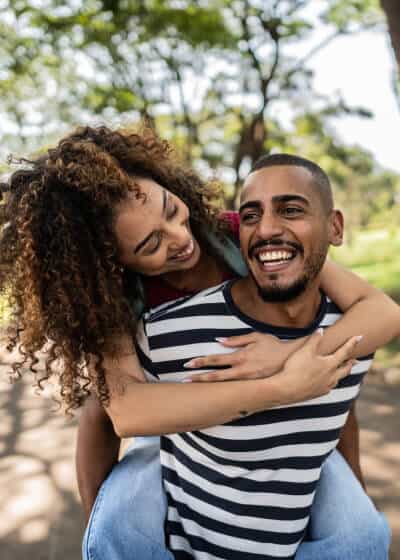 Woman wrapping arms around man outdoors.
