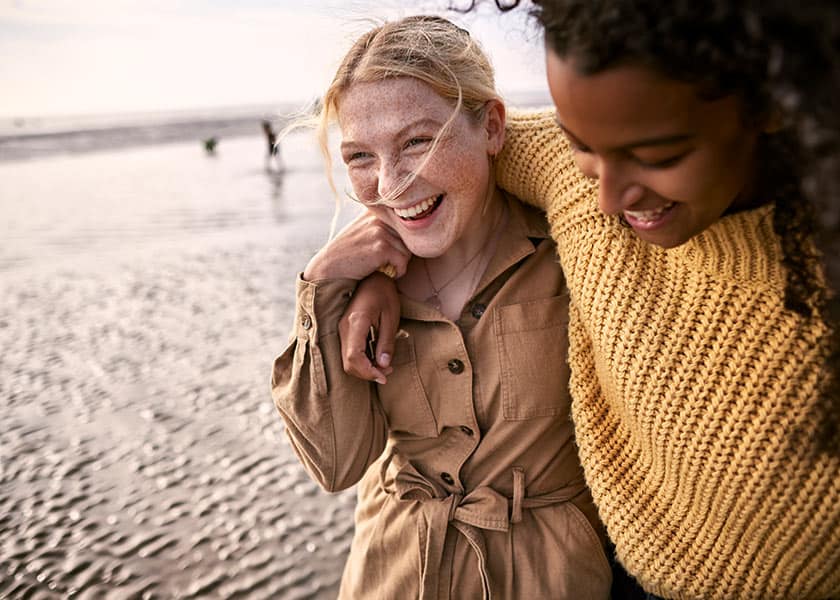 Girls with arms around each other on beach