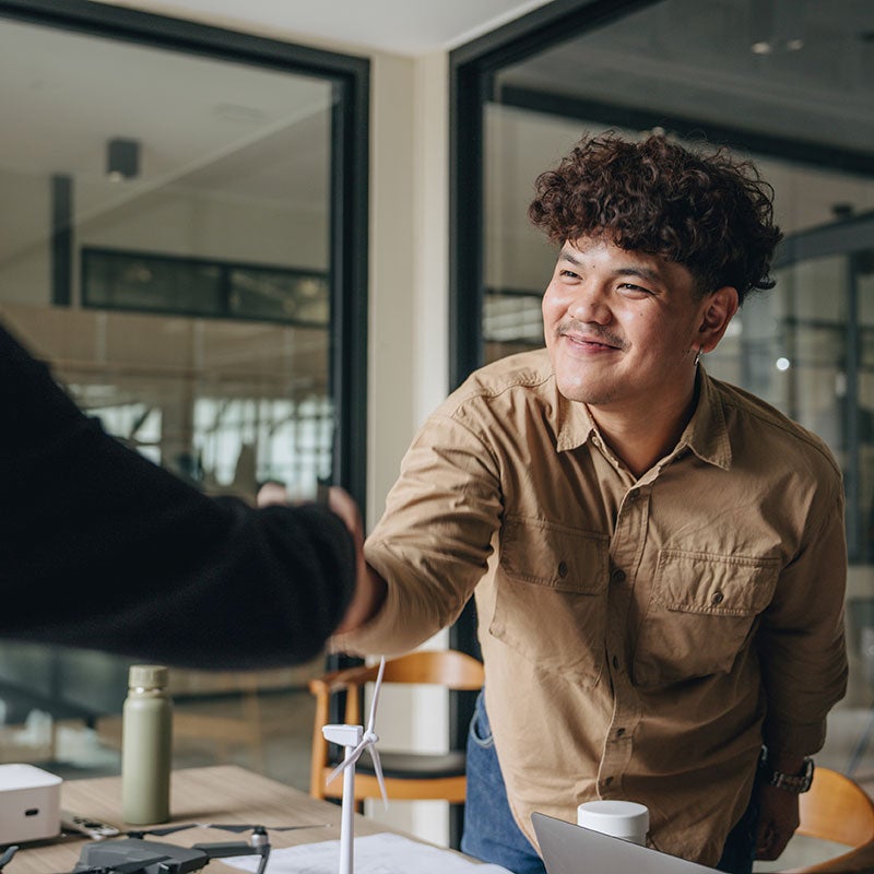 Man shaking someones hand across a desk