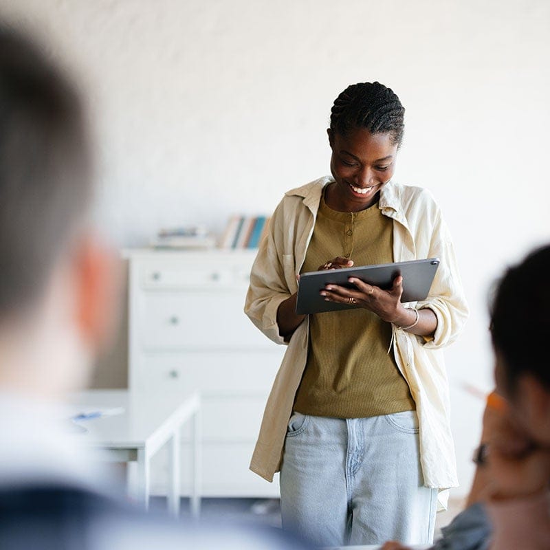 Woman on computer tablet in front of class