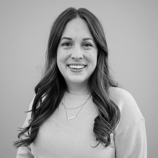 Woman with long hair wearing a light sweater, smiling at the camera against a plain background. Black and white photo.