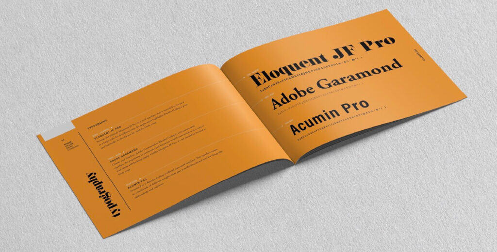 An open orange booklet displays different font names and typography samples on a textured gray surface.