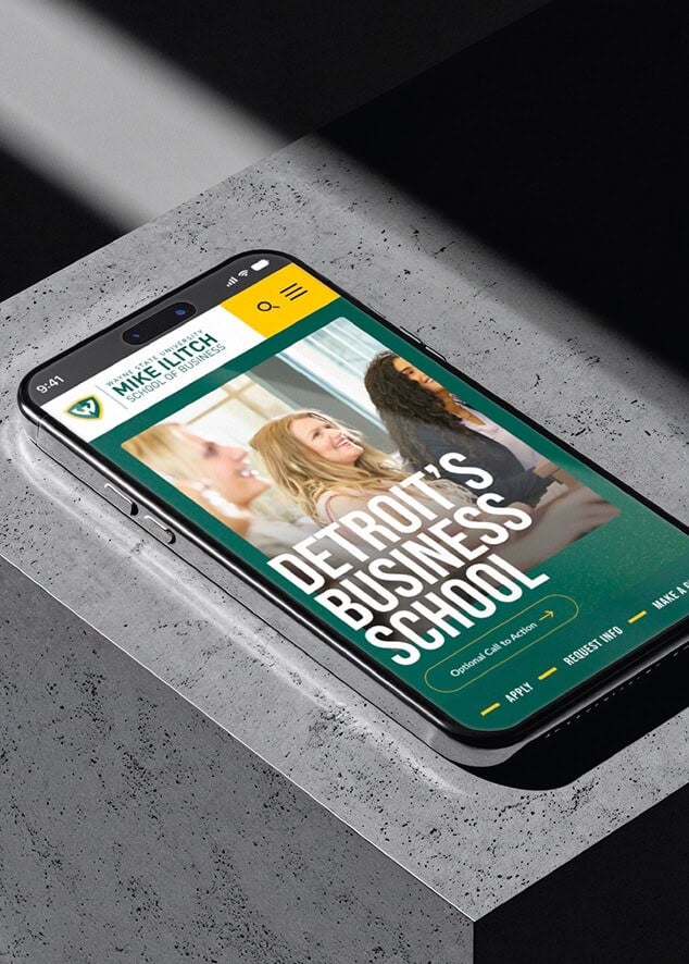 A smartphone displays a website for Detroit’s Business School with students smiling on the homepage.