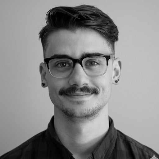 Young man with glasses and a mustache smiling slightly, wearing a dark shirt, against a plain background.