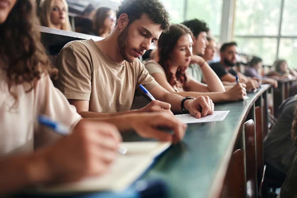 A group of people sitting in a classroom writing on paper.