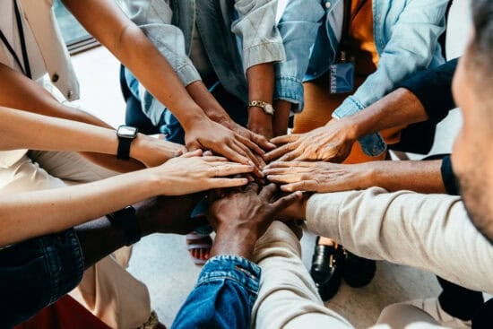 A group of diverse people join hands together in a circle, symbolizing unity and teamwork.