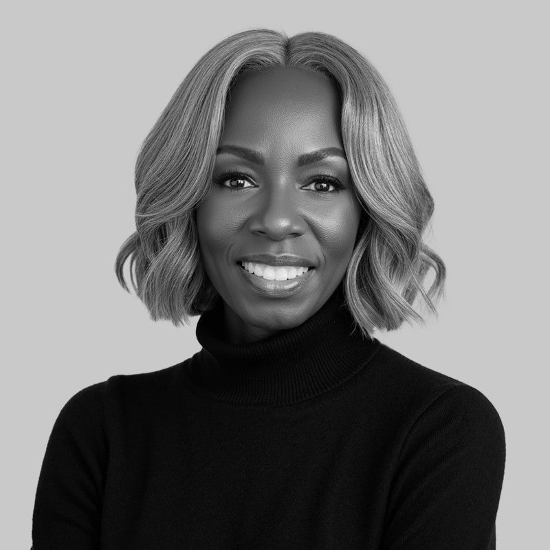 Smiling woman with wavy, shoulder-length hair wearing a black turtleneck, posed against a plain background.