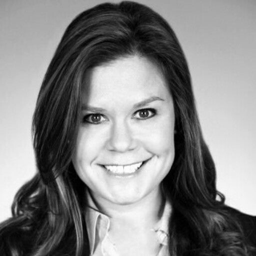 Smiling woman with long hair in a suit, pictured in black and white, facing the camera.