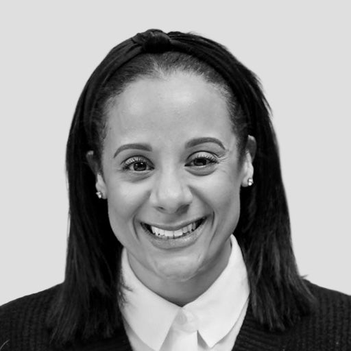 Smiling woman with straight dark hair, wearing a white collared shirt and earrings, on a light background.